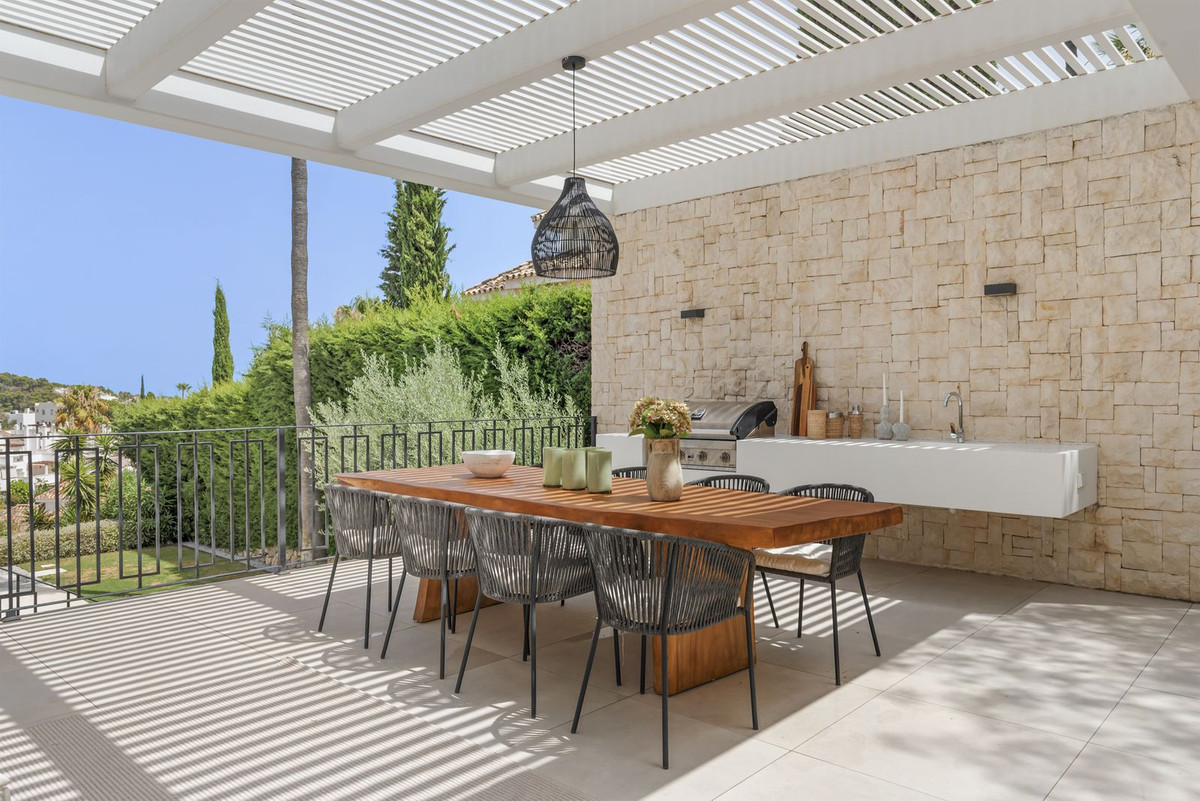 Outdoor kitchen with gas grill and dining table under the pergola