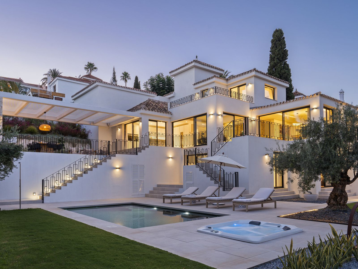 Villa at dusk with facade, pool and garden lighting on